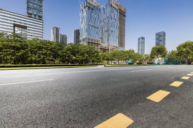 Panoramik siluet ve boş yolu, boş beton zemini olan modern iş binaları.