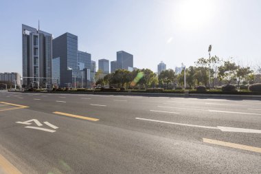 Panoramik siluet ve boş yolu, boş beton zemini olan modern iş binaları.