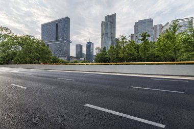 Panoramik siluet ve boş yolu, boş beton zemini olan modern iş binaları.