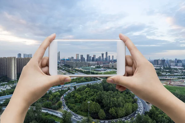 Businessman hand holding empty screen smart phone with city back