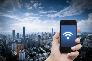 El akıllı telefon ve şehir arka planda internet WiFi ağ bağlantısı iletişim teknolojisini kullanarak