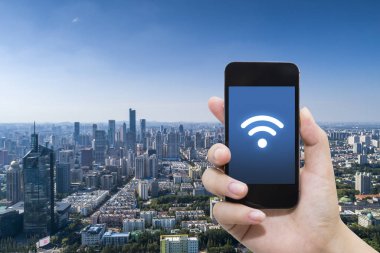 El akıllı telefon ve şehir arka planda internet WiFi ağ bağlantısı iletişim teknolojisini kullanarak