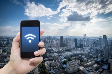 El akıllı telefon ve şehir arka planda internet WiFi ağ bağlantısı iletişim teknolojisini kullanarak