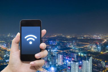 El akıllı telefon ve şehir arka planda internet WiFi ağ bağlantısı iletişim teknolojisini kullanarak