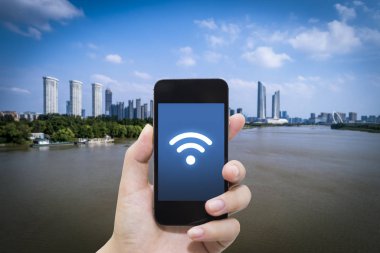 El akıllı telefon ve şehir arka planda internet WiFi ağ bağlantısı iletişim teknolojisini kullanarak