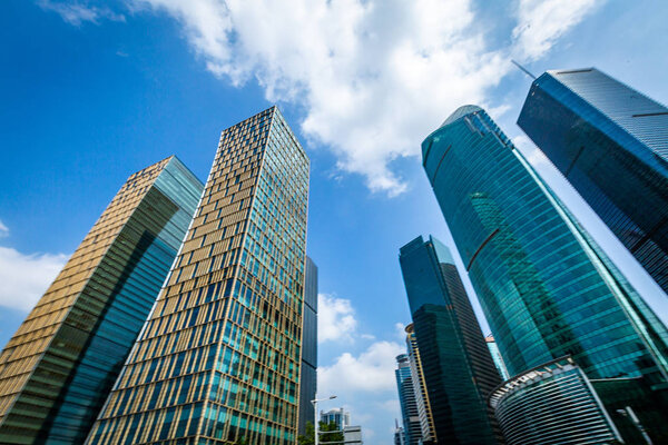 Bottom view of modern skyscrapers in business district against blue sky