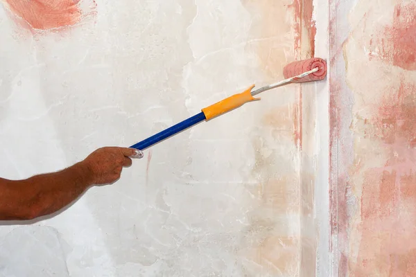 Boya silindirli erkek eli duvara astar uygular.