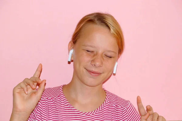 听音乐的少女 眼睛紧闭在耳机上 面带微笑 粉红背景的肖像 — 图库照片