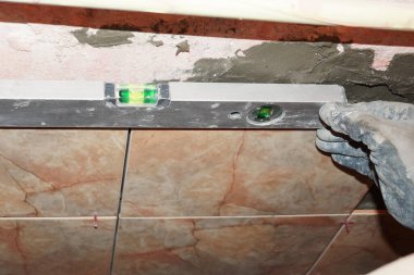 Adam kiremitlerin eşitliğini kontrol ediyor.