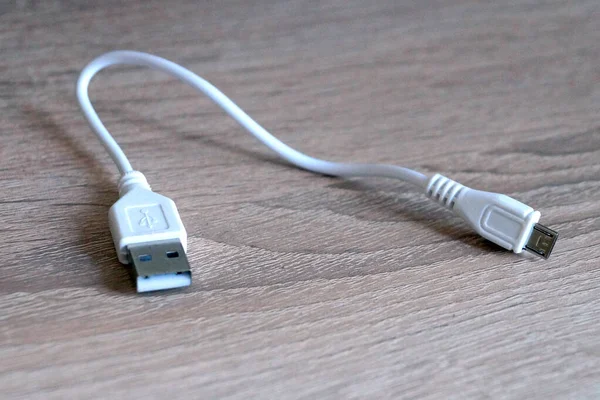 white usb cable on a wooden table close-up