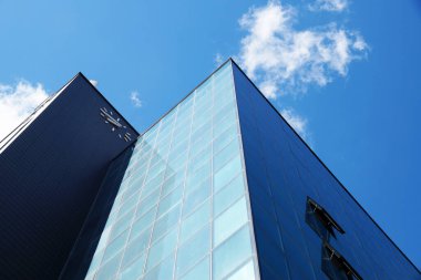 Güneşli bulutlu gökyüzünün arka planına karşı modern gökdelen cephesi