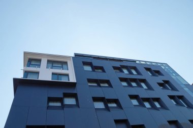 Güneşli bulutlu gökyüzünün arka planına karşı modern gökdelen cephesi.