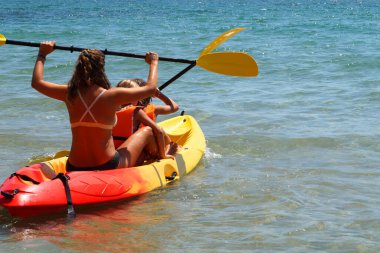Denizde kayak yapan iki çocuklu bir kadın.