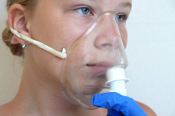 девушка дышит через ингалятор, портрет крупным планом