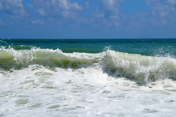 big white waves hitting the sea shore on the sunny day