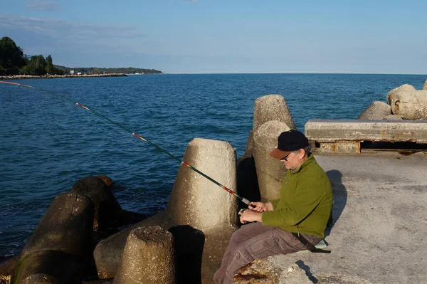 Mann Sitzt Auf Einem Pier Und Fischt Die Sich Drehen — Stockfoto