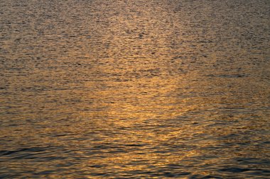 Batan güneş karanlık deniz suyuna yansıyor..