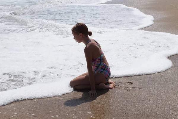 10代の少女はぬれた砂の上に座って海を見て — ストック写真