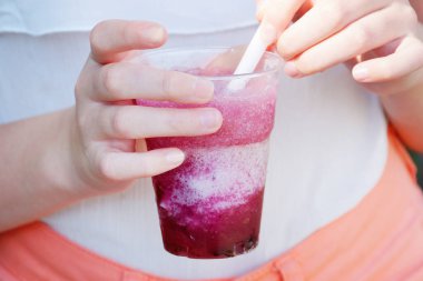 Parktaki bir kızın elinde pipetle canlandırıcı meyve suyu..