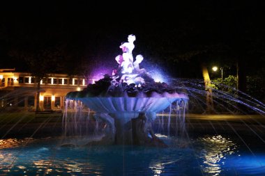 Bir yaz gecesinde aydınlatılmış heykelleri olan çeşme..