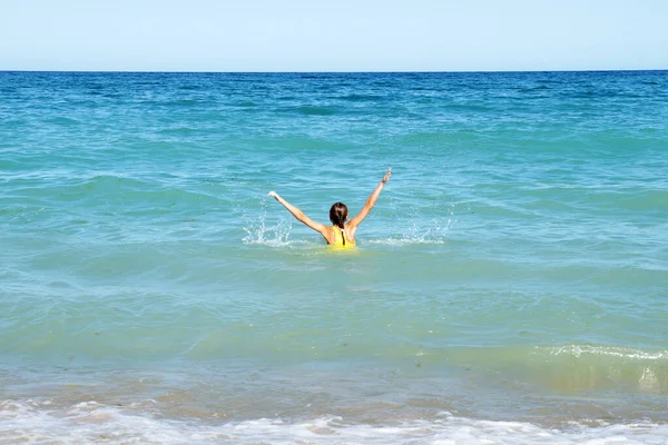 海の中に手を上げている少女リアビューコピースペース — ストック写真