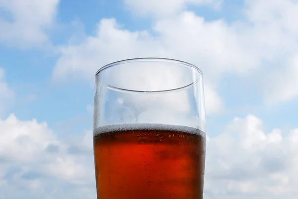 glass with beer on the background of a light cloudy sky