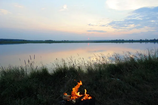 bonfire by the lake in the evening on the background of sunset