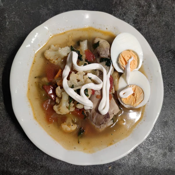 Sebzeli tavuk çorbası, yumurta ve mayonez, beyaz tabakta, üst manzara..