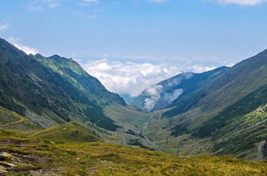 Transfagarasan yolun Fagaras Dağları, yeşil çim ve kayalar, Karpatlar bulutlarda doruklarına.