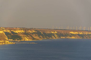 Yeşil Trakya kayalıklarla sarı toprak, Karadeniz'in mavi açık suya yakın rüzgar çiftlikleri.