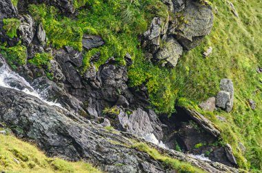 Transfagarasan yolun Fagaras Dağları, yeşil çim ve kayalar, Karpatlar bulutlarda doruklarına.