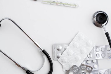 Eski bir cıva termometre ilaçlar ve beyaz izole zemin üzerinde eski bir stetoskop ile. Üstten Görünüm