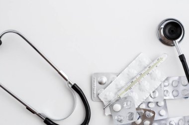 Eski bir cıva termometre ilaçlar ve beyaz izole zemin üzerinde eski bir stetoskop ile. Üstten Görünüm