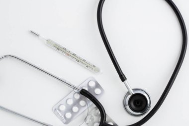 Eski bir cıva termometre ilaçlar ve beyaz izole zemin üzerinde eski bir stetoskop ile. Üstten Görünüm