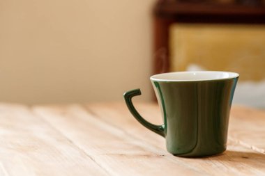 Sabah kahve koyu yeşil şık Kupası bir tahta üzerinde arka plan dokulu. Kış güneş ışığı ışınlarının fotoğrafı