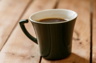 Sabah kahve koyu yeşil şık Kupası bir tahta üzerinde arka plan dokulu. Kış güneş ışığı ışınlarının fotoğrafı