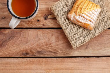 Çay bir fincan ve ahşap bir masa üzerinde bir tuval üzerine süzme peynir ile bir pasta