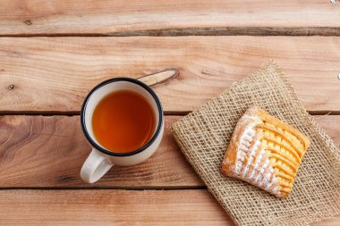 Çay bir fincan ve ahşap bir masa üzerinde bir tuval üzerine süzme peynir ile bir pasta