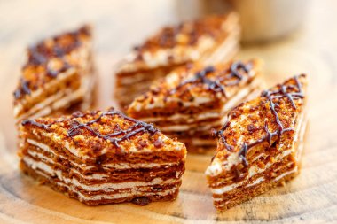 Dilim kek katmanları ile bir bardak çay ahşap bir masa üzerinde krem ile