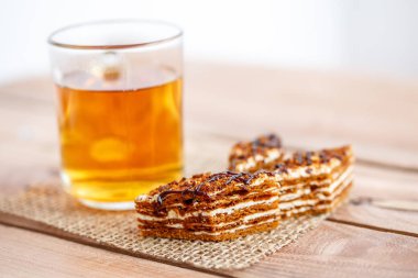 Dilim kek katmanları ile bir bardak çay ahşap bir masa üzerinde krem ile