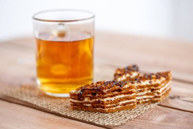 Dilim kek katmanları ile bir bardak çay ahşap bir masa üzerinde krem ile
