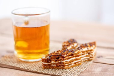 Dilim kek katmanları ile bir bardak çay ahşap bir masa üzerinde krem ile