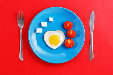 Kavramı için aşk hikayeleri ve Sevgililer günü için. Kızarmış yumurta, peynir ve domates ile mavi bir plaka üzerinde bir kalp şeklinde.