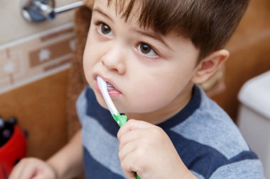 Küçük şirin çocuk banyoda Dişlerini fırçalıyor.