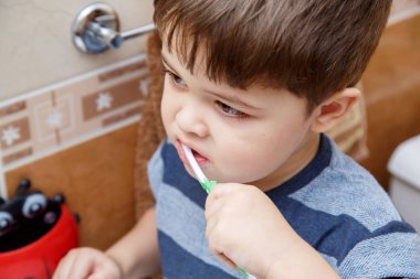 Küçük şirin çocuk banyoda Dişlerini fırçalıyor.