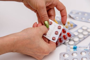 Tıp için kavram. Yaşlı bir kadın elinde farklı ilaçlar arasında doğru ilaç seçin.