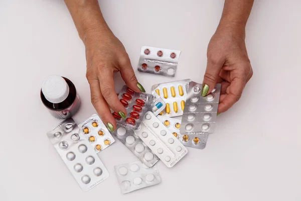 Concept for medicine. The hands of an elderly woman choose the right medicine among different drugs.