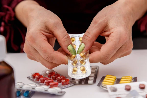 Concept for medicine. The hands of an elderly woman choose the right medicine among different drugs.