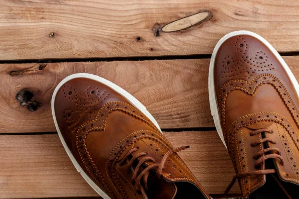 Brown men's shoes on wooden background. Top view