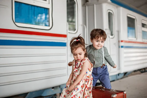 Photo shoot in vintage style. Boy and girl in vintage clothes with vintage accessories on abandoned railway and train station